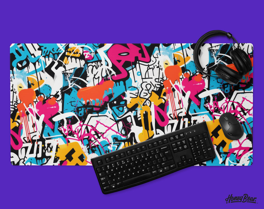 High-impact, large-format desk mat with a vibrant graffiti design, splashed with electric blues, pinks, and yellows, set against a black backdrop – Honey Bear