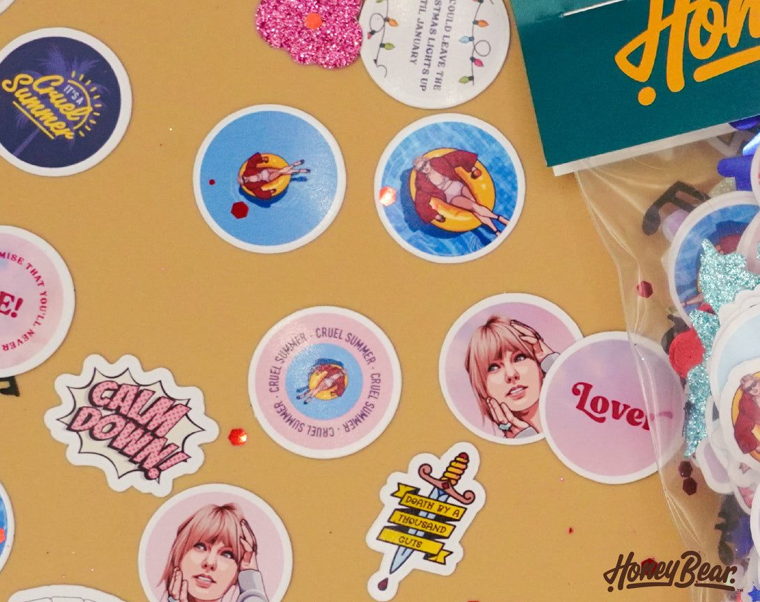Taylor Swift party confetti spread out on a tabletop | Confetti pieces feature imagery and songs from taylor swift lover album