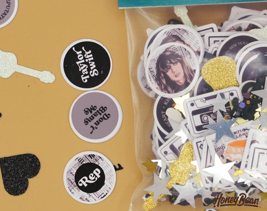 Taylor Swift party confetti spread out on a tabletop | Confetti pieces feature imagery and songs from reputation album